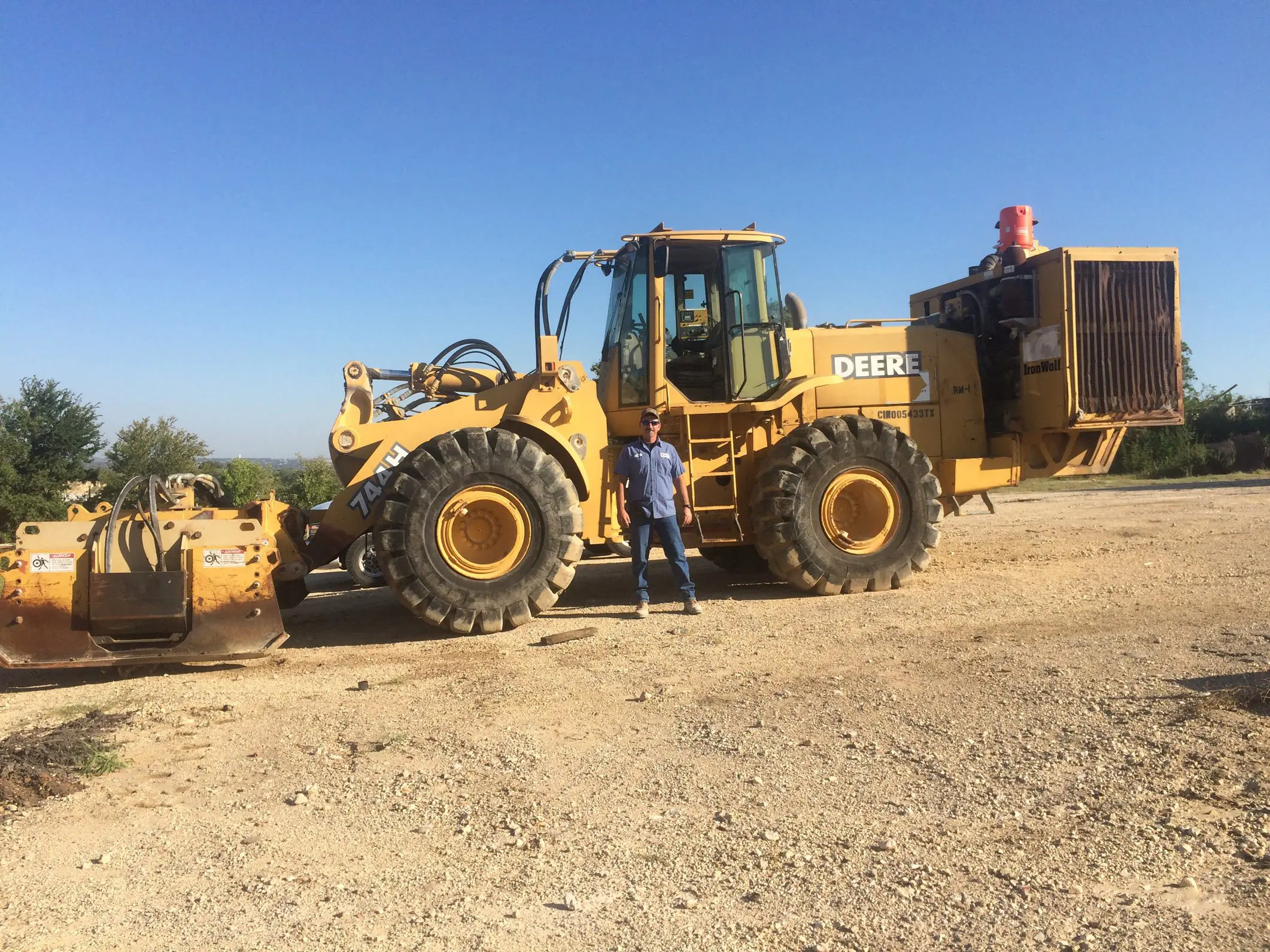 A man standing next to a large yellow tractor.